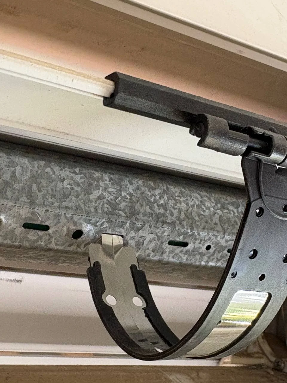 Close-up of a screwless roller-shutter hanger clipped into a slot in the metal roller tube