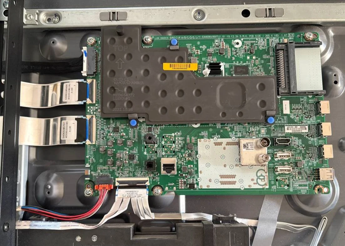 The EBU66095002 main board installed inside my LG OLED65CX5LB, with its vapor chamber and ribbon cables visible